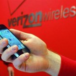 Employee holds out an iPhone for a customer at a Verizon store in Boston